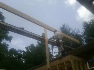 Carpenter setting a ridge beam over a new addition frame — Ice Dam Removal by Roofing Brothers in Saulsbury