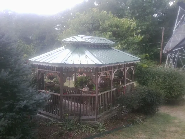 Green metal roof on a backyard gazebo surrounded by garden beds in Saulsbury