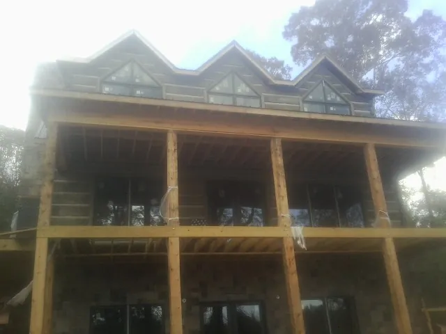 Dormers and porch framing on a large log home under construction — Roof Coating work by our crew in Saulsbury