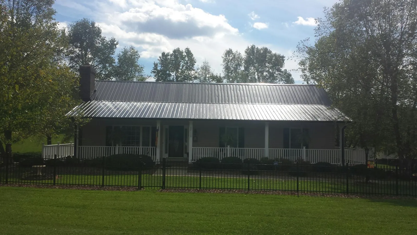 Gray metal roof on a brick ranch with a full width front porch — Gutter Guard Installation work by our crew in Saulsbury