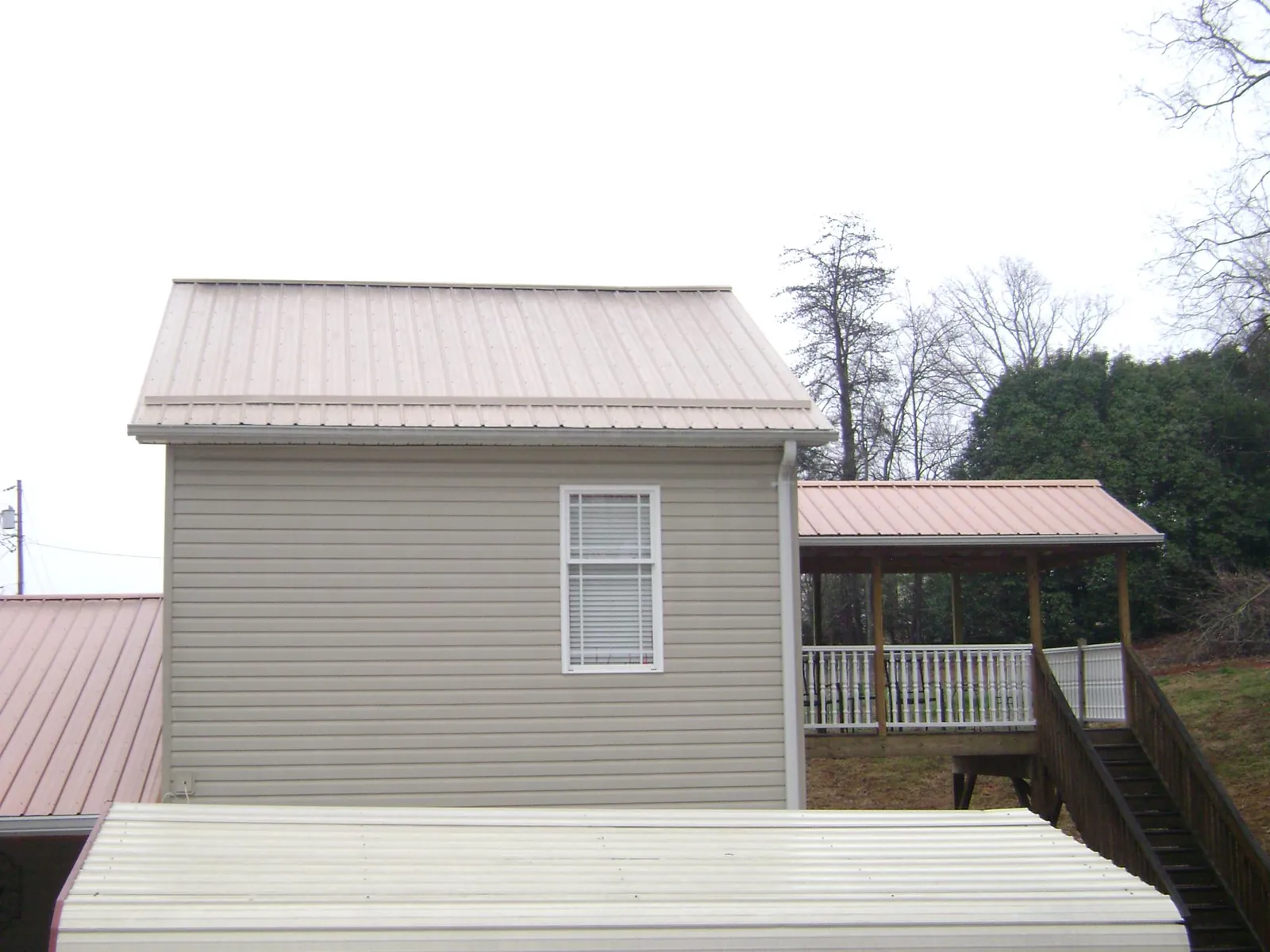 Tan metal roofs on a two story addition and attached porch, from a Roof Replacement job in Saulsbury