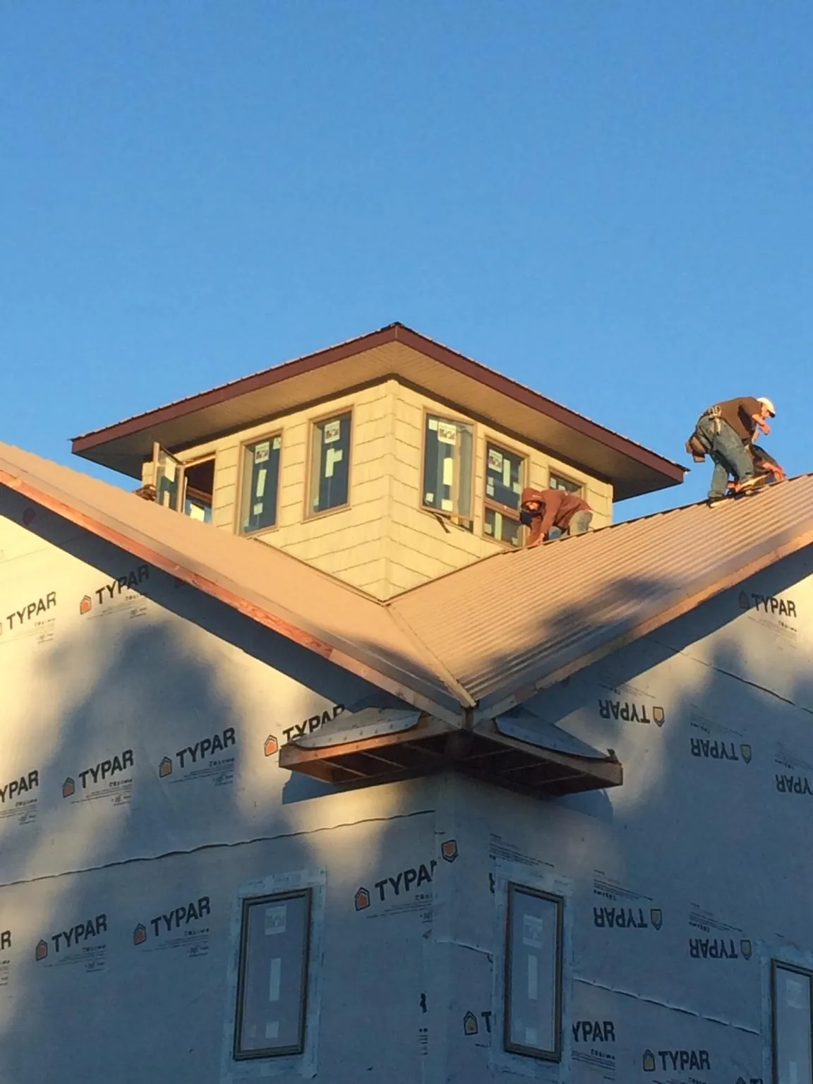Roofers working around a rooftop cupola on a new metal roof at sunset — Roof Waterproofing in Saulsbury by Roofing Brothers